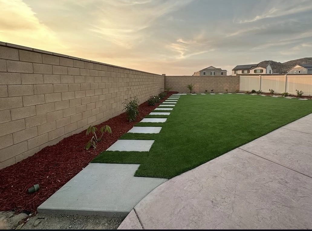 Finished backyard with artificial turf, paver walkway and stamped concrete